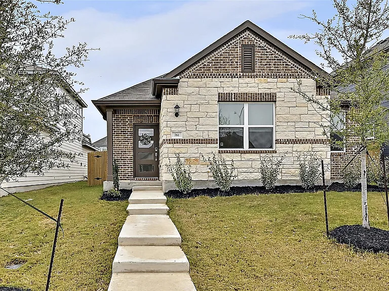 Single-story brick and stone house with a front lawn and pathway.